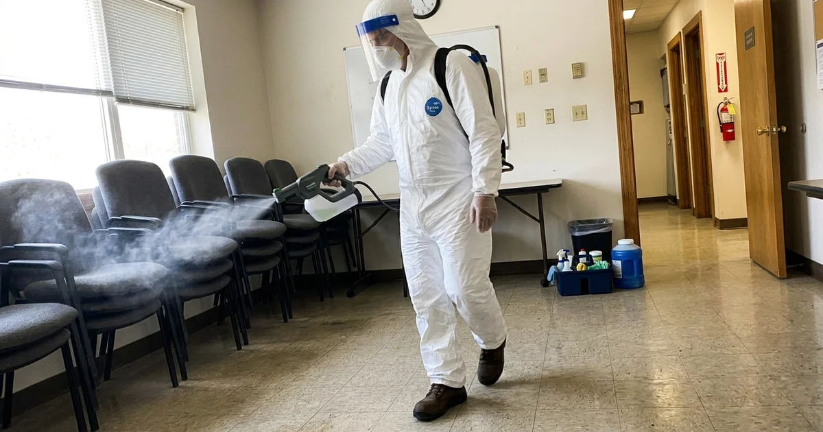 Technician applying disinfectant with an electrostatic sprayer in a commercial space