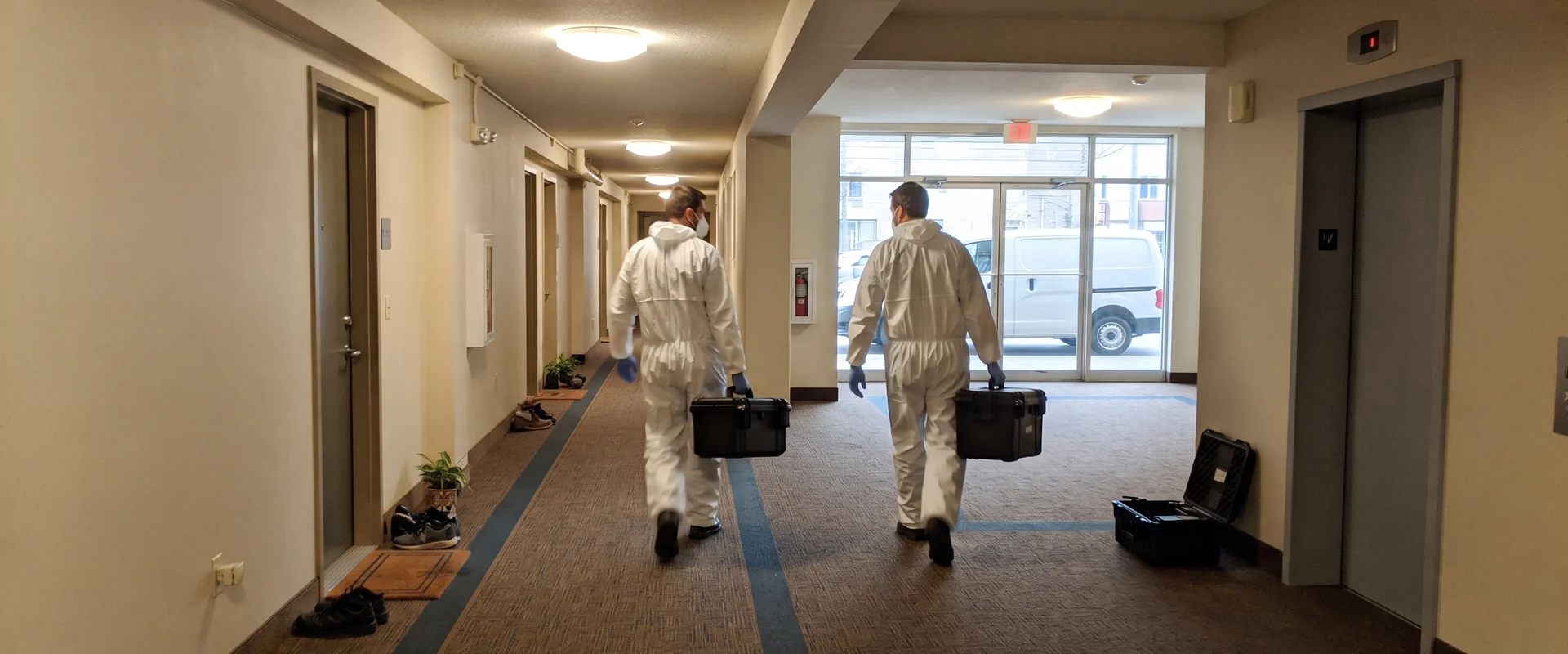 Technicians discreetly carrying remediation equipment into an apartment building